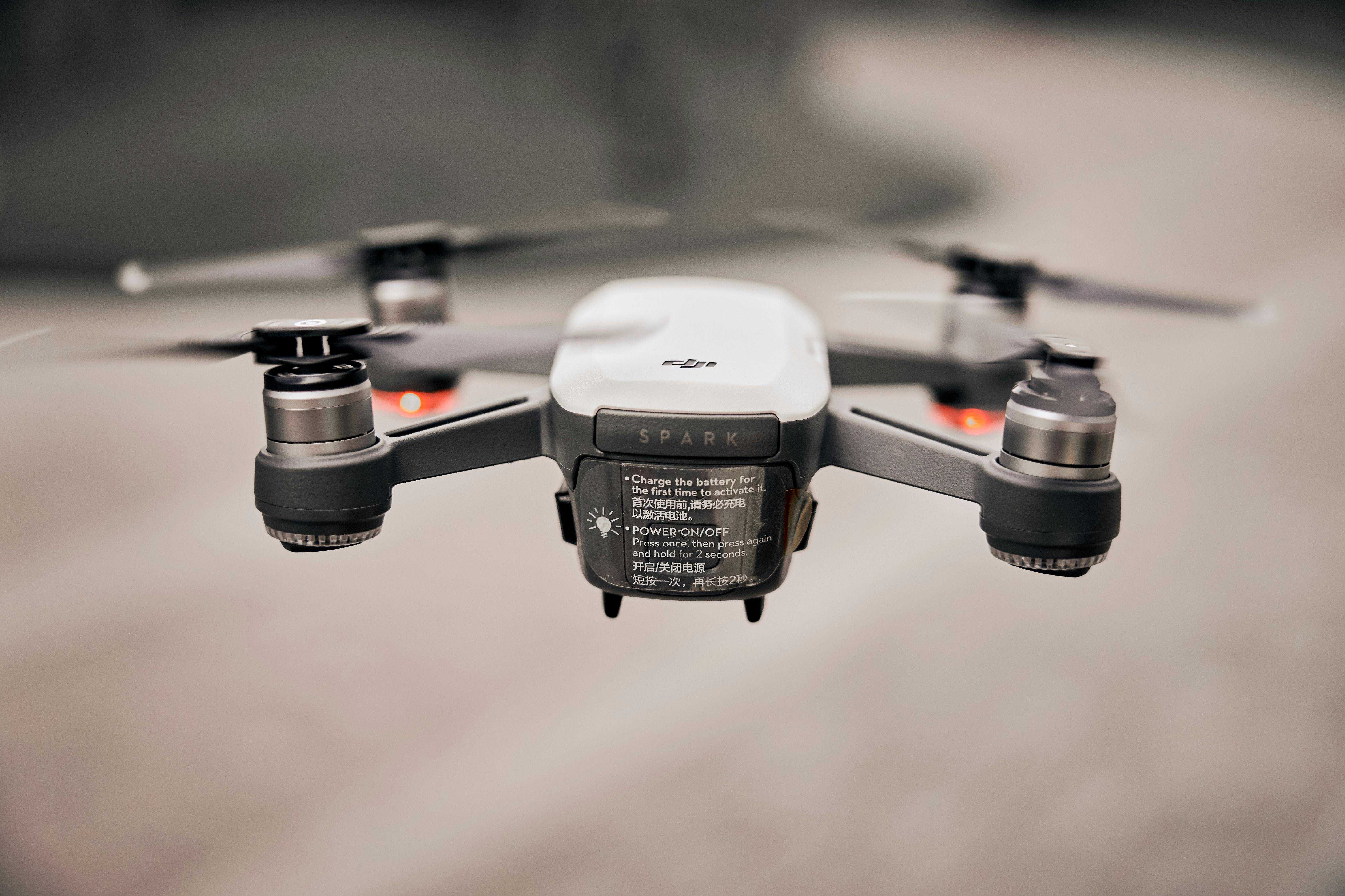 Dron negro con tapa blanca, volando con las aspas activas.