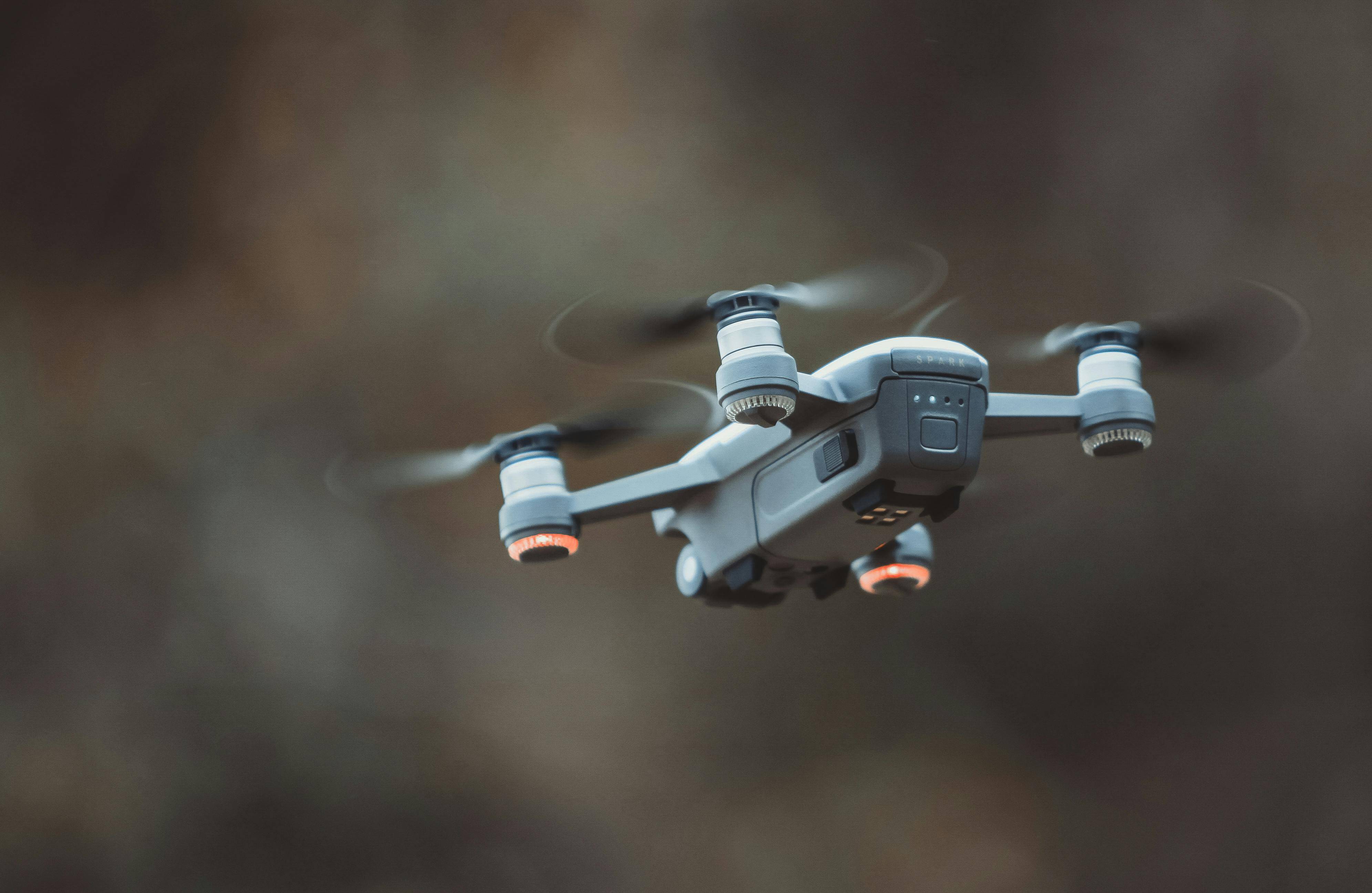  Dron gris con luces naranjas y aspas en movimiento